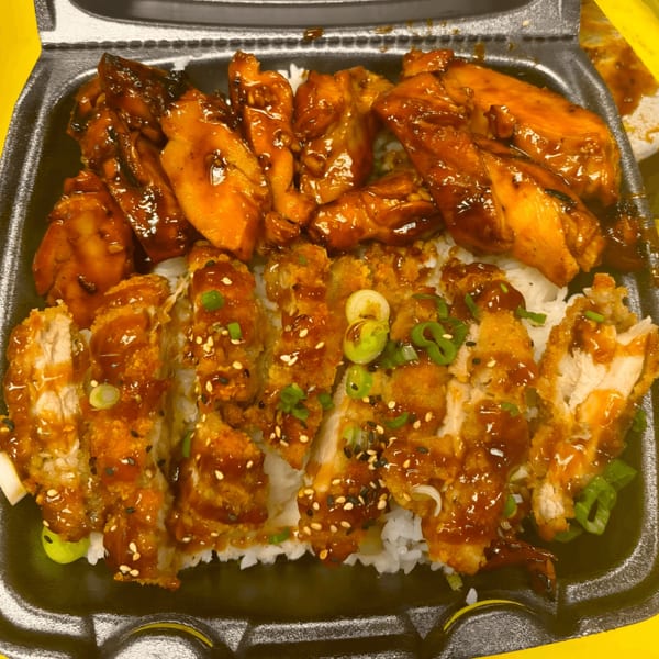 Teriyaki chicken and crispy chicken katsu with sauce, sesame seeds, and green onions over rice.